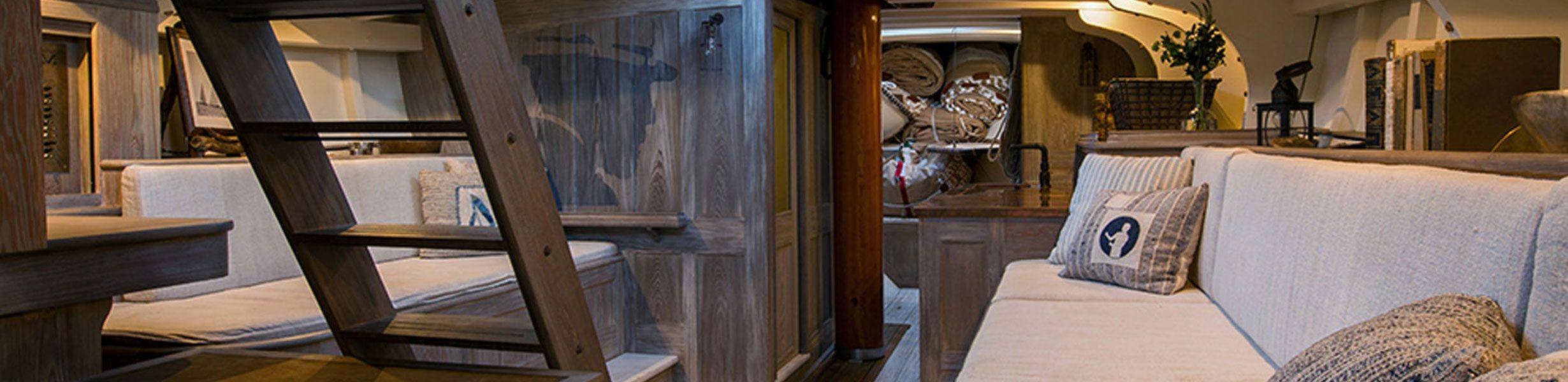 a beautiful wood paneled, spacious interior of a sailing yacht with brown and beige accents.